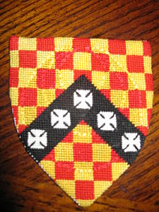 Klaus von Mainz Checky gules and Or, on a chevron sable five crosses formy argent (registered 12/01). Maker: Louise of Woodsholme The shield is diapered with a crescent worked in chain-stitch.
