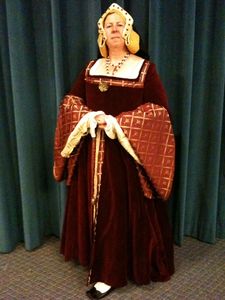 Tudor Dress Baroness Ceara in a crimson Tudor gown, made in the likeness of Jane Seymour, Henry VIII's second wife. The suit includes chemise, gown, forepart, gable headdress, jewelry, and shoes.