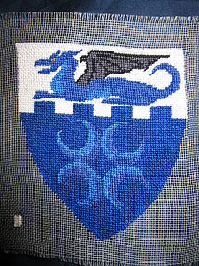 Bruce Draconarius Azure, on a chief embattled argent a dragon couchant azure winged sable, as an augmentation the dragon maintaining between its forefeet an escutcheon azure charged with four crescents conjoined in saltire, horns outward argent. (registered 10/81). Maker: Astra Christiana Benedict