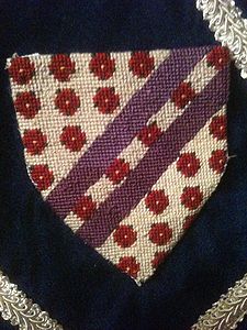 Caitlin Christiana Wintour Argent, semy of roses gules, barbed and seeded proper, two scarpes purpure. (registered 9/87). Maker: Caitlin Christiana Wintour; canvas painted by Louise of Woodsholme.