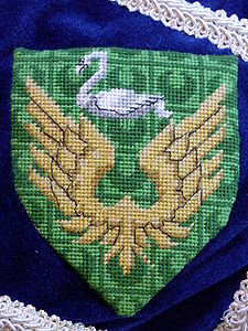 Mela de Prion Vert, a pair of wings conjoined Or and in chief a swan naiant argent (registered 11/86).
